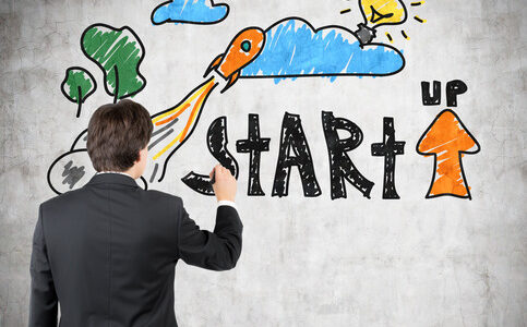 startup businessman drawing startup concept on concrete wall
